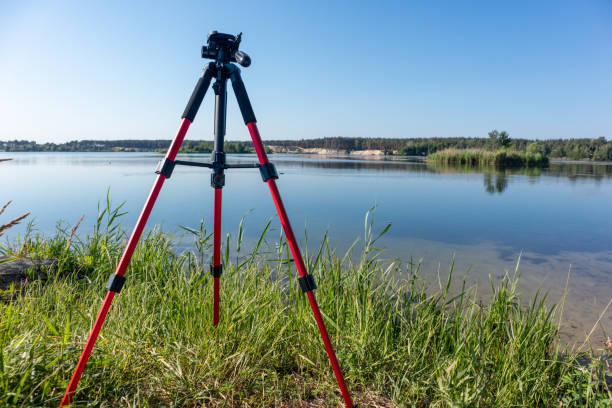 istock Camera red tripod standing near lake water setup 1283506010