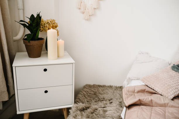 istock Room interior with bedside table, plant, and candles. Bedroom interior with a bed and bedside tables. Autumn comfort. Winter elements of home decor. 1283507581