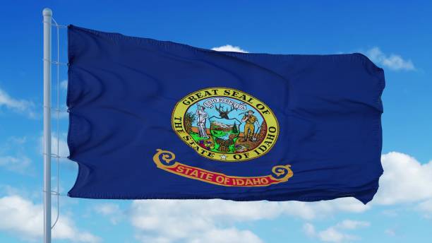 istock Idaho flag on a flagpole waving in the wind, blue sky background. 3d rendering 1283509663
