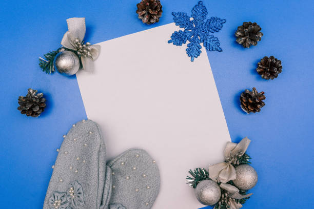 istock Christmas composition on a blue background with pine cones, mittens, a garland, Christmas decorations and a blank sheet of paper for text. New year concept 1283509832