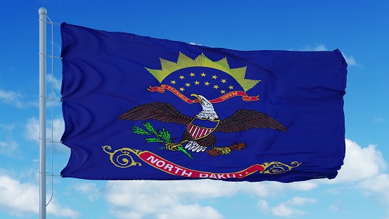 Bandera de Dakota del Norte en un asta de bandera ondeando en el viento, fondo del cielo azul. Renderizado en 3D photo