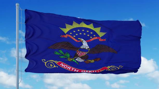 bandera de dakota del norte en un asta de bandera ondeando en el viento, fondo del cielo azul. renderizado en 3d - north dakota fotografías e imágenes de stock