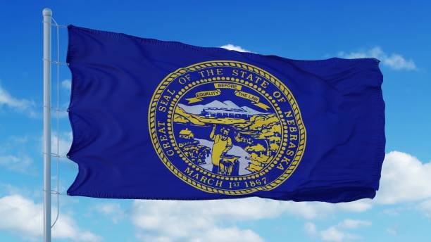 istock Nebraska flag on a flagpole waving in the wind, blue sky background. 3d rendering 1283510097