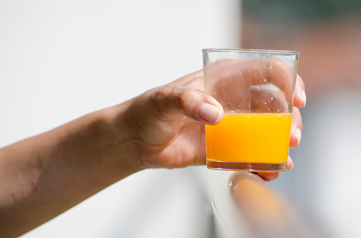 Woman Hand Holding a Glass of Orange Juice in Switzerland.