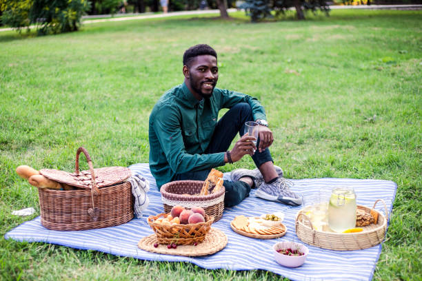 Attractive black ma on picnic at sunny day. He is enjoying tasty food and good weather.