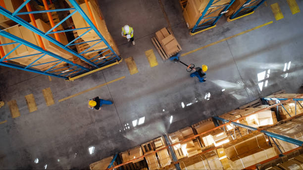 top-down view: in warehouse people working, forklift truck operator lifts pallet with cardboard box. logistics, distribution center with products ready for global shipment, customer delivery - em cima de imagens e fotografias de stock