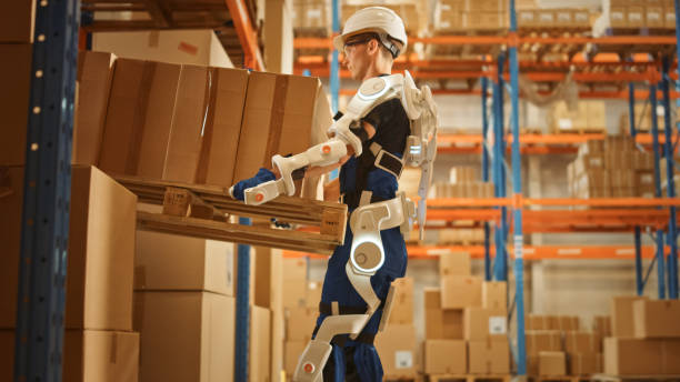 High-Tech Futuristic Warehouse: Worker Wearing Advanced Full Body Powered exoskeleton, Lifts Heavy Pallet full of Cardboard Boxes. Delivery Exosuit amplifies strength. High-Tech Futuristic Warehouse: Worker Wearing Advanced Full Body Powered exoskeleton, Lifts Heavy Pallet full of Cardboard Boxes. Delivery Exosuit amplifies strength. powered exoskeleton photos stock pictures, royalty-free photos & images