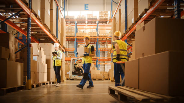 retail warehouse full of shelves with goods in cardboard boxes, workers scan and sort packages, move inventory with pallet trucks and forklifts. product distribution logistics center. - logistical imagens e fotografias de stock