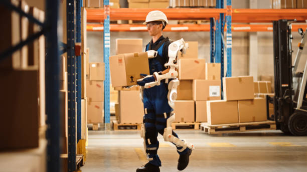 High-Tech Futuristic Warehouse: Worker Wearing Advanced Full Body Powered exoskeleton, Walks with Heavy Cardboard Box. Exosuit amplifies Human Performance, strength, Eliminates Work Related Injuries almacén futurista de alta tecnología: trabajador que lleva exoesqueleto avanzado con cuerpo completo, camina con caja de cartón pesada. el exotraje amplifica el rendimiento humano, la fuerza, elimina las lesiones relacionadas con el trabajo