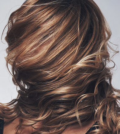 Shot of a woman's hair covering her face while posing against a grey background