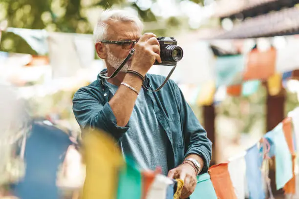 Photo of A European senior tourist photographs prayer flags in Nepal