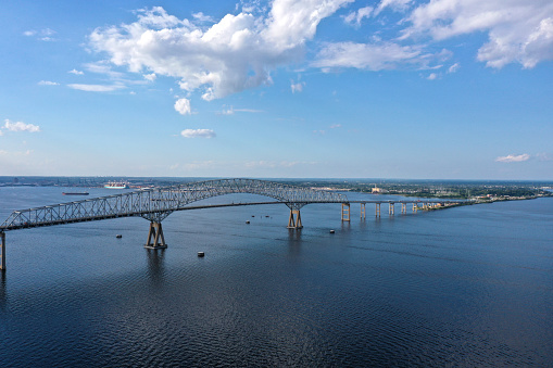 Key bridge seen from an aerial view. A bright blue sky with white puffy clouds are seen above.