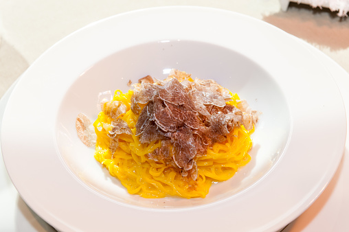 the white truffle from Alba in Italy sliced on a plate of egg pasta tagliolini-spaghetti