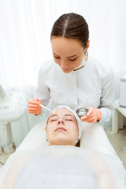 Portrait Cosmetologist applying mask on client's face in spa salon. Wellness center. Healthcare occupation Cosmetologist applying mask on client's face in spa salon. Wellness center. Healthcare occupation facial chemical peel stock pictures, royalty-free photos & images