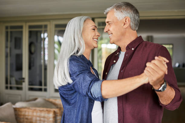 Happy couple dancing in balcony during COVID-19 Smiling mature man and woman dancing during state of emergency. Romantic couple is spending leisure time. They are in balcony during coronavirus lockdown. middle aged couple dancing stock pictures, royalty-free photos & images
