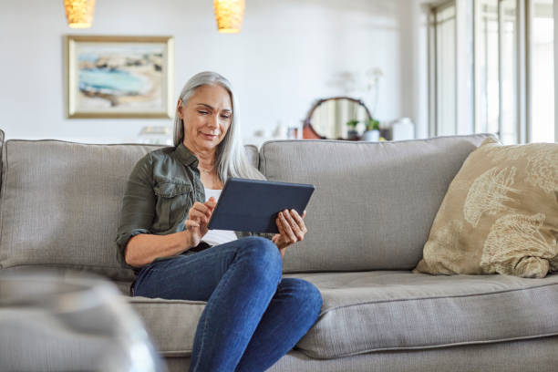 istock Smiling mature woman using digital tablet at home 1283520752
