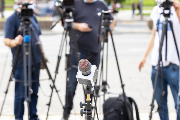 istock Microphone in focus at news conference, blurred camera operators in the background 1283520990