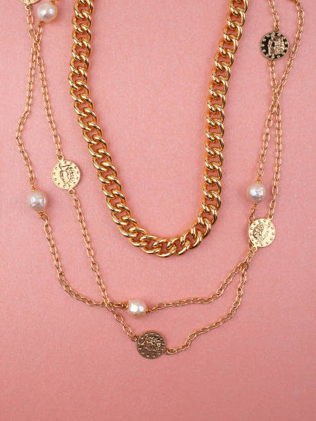 istock Two women`s gold necklaces on shimmering pink background 1283521892