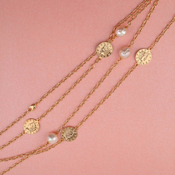 istock Two women`s gold chain necklaces on shimmering pink background 1283521899