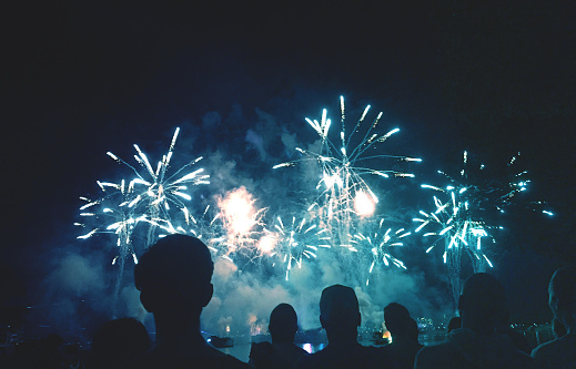 Crowd of Silhouetted People Watching a Colorful Blue Fireworks Display for New Years or Fourth of July Celebration Event, Horizontal, Copy Space