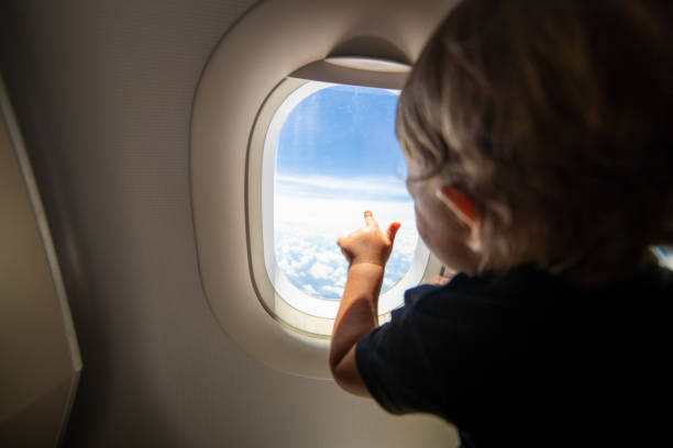 istock cute toddler points his finger at the sky through the window. first flight concept, traveling with children. 1283524744