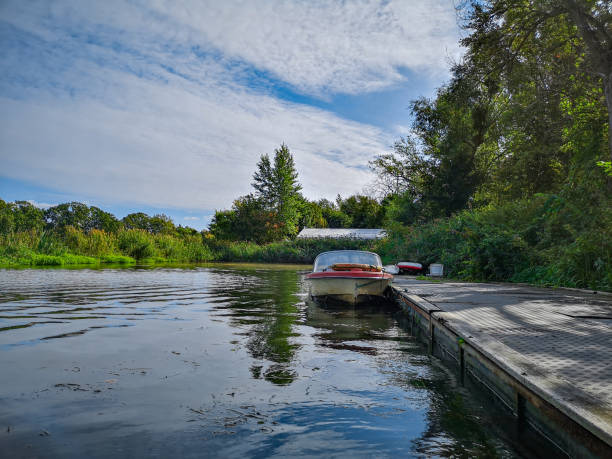 istock Old boat near wooden platform on river between bushes and trees 1283524858
