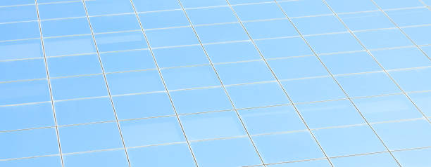 istock Office building facade, clean square glass blue window panes abstract background texture Simple square glass pane pattern with soft light reflections, no clouds, corporate building light blue backdrop 1283525144