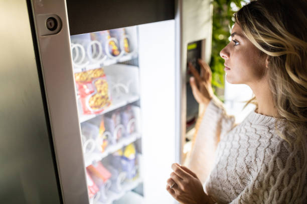 empresaria comprando un aperitivo de la máquina expendedora - vending machine fotos fotografías e imágenes de stock