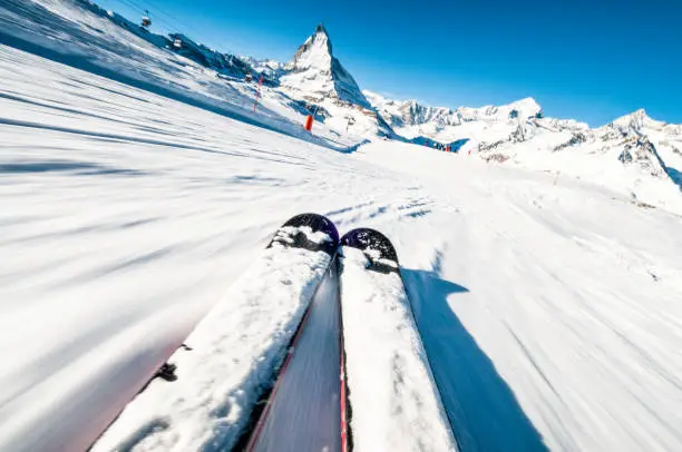 A skier's perspective on a ski piste at speed, with motion blur in the foreground.
