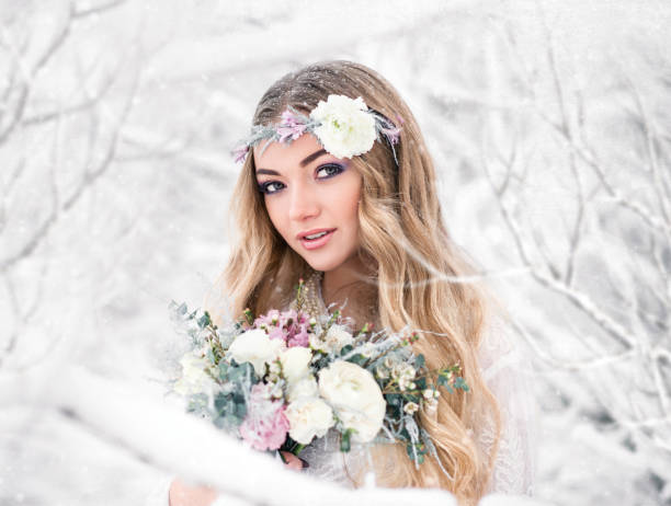 süße braut im winter schneewald im freien mit schönen blumen auf dem kopf und einem blumenstrauß. hochzeit make-up - christmas wedding bride winter stock-fotos und bilder