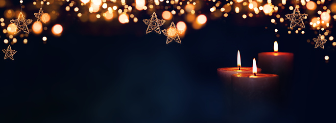Burning candles in christmas night with golden stars and bokeh for a background concept. Space for your text.