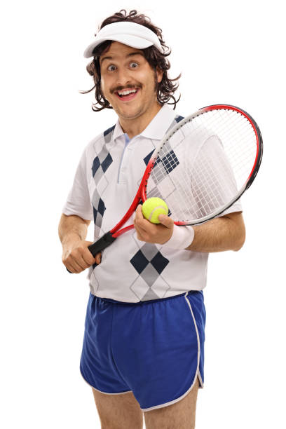 A middle-aged man dressed in casual activewear holds a racket and bag in a green, sunny park, portraying his interest in outdoor sports and fitness activities.