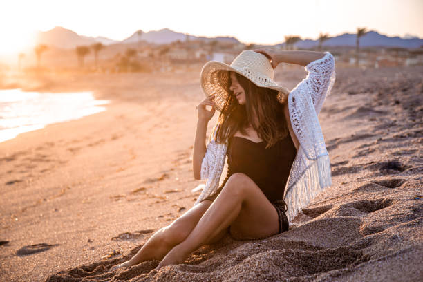 istock Beautiful boho model in a hat poses on the beach in the sun 1283531525