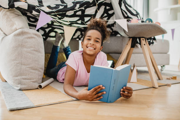 istock Little girl reading a book at home 1283531678