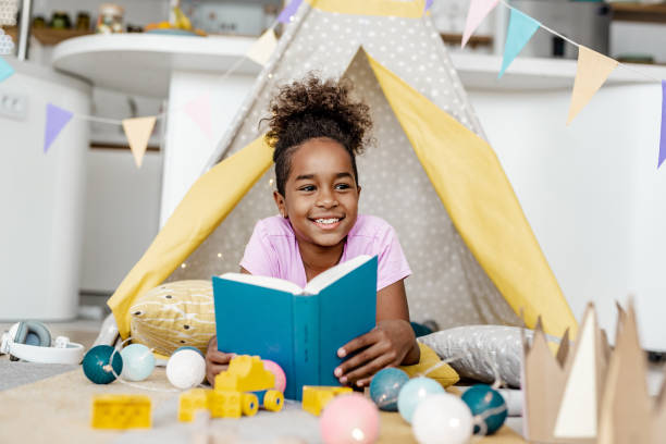 istock Little girl reading a book at home 1283531996