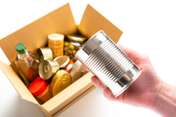 recoger a mano una lata de metal de la caja de cartón de alimentos no perecederos - non perishable fotografías e imágenes de stock