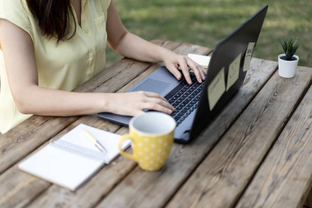 istock Young woman using laptop computer in the public park - Millennial female freelancer working remotely behind a close-up laptop in a city park - Technology and remote work concept - Using tech devices 1283533538