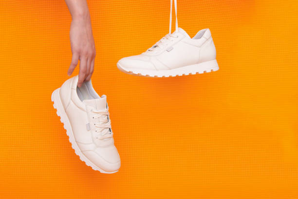 istock white sneakers suspended from a bright orange background, selective focus 1283533630