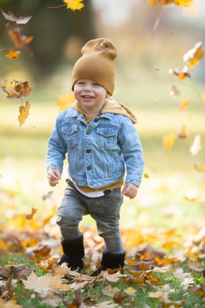 istock Small boy laughs at foliage around him on a chilly fall day. 1283538151