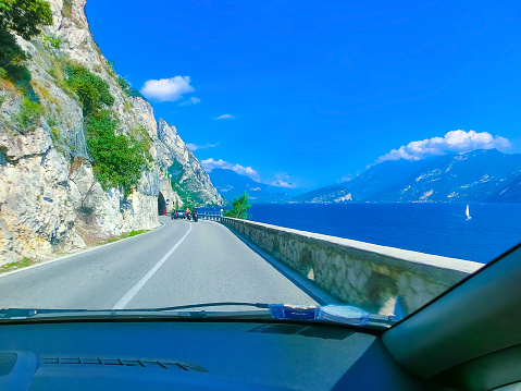 Limone sul Garda, Italy - September 21, 2014: High mountains and road on the shore, Lake Garda, Italy, Europe. view through the windshield of car