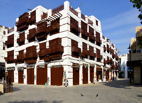 Jeddah, Mecca Region, Saudi Arabia: Souk Al Alawi - hedjazi architecture in Al Balad district - building with stores and Arabian closed balconies (rowshan - rawasheen / mashrabiyas), Historic Jeddah, the Gate to Makkah, UNESCO world heritage site. Red Sea coastal coral architecture tradition.