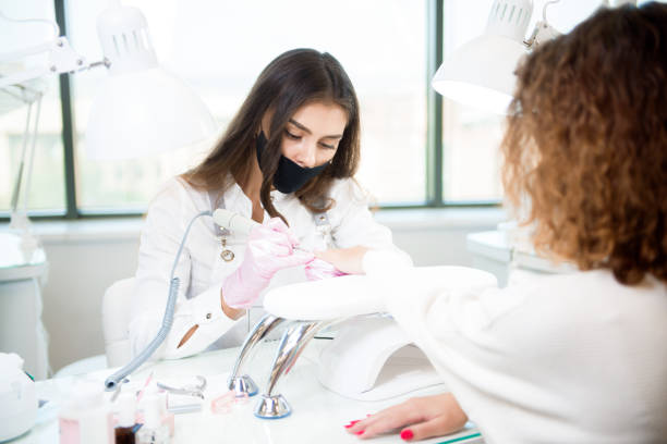 istock Professional manicure master in protective face mask using electric nail polisher tool for glazing treatment manicure procedure. 1283539847