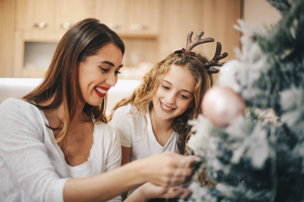 istock Two girls putting decoration on Christmas tree. 1283539918