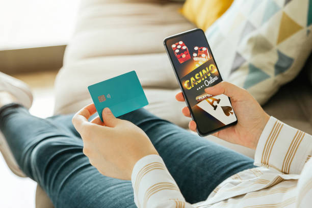 stok foto seorang wanita akan bermain kasino online dan memegang kartu kredit untuk membayar. konsep perjudian dan taruhan online - judi online potret stok, foto, & gambar bebas royalti