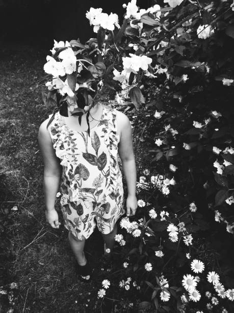 Happy girl rejoices summer. Young child playing outside with white jasmine flowers. Summertime day activity. Happy, joyful kid outdoors. Having fun alone. Beautiful, scenic forest landscape.