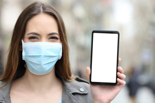 istock Happy woman wearing mask showing blank phone screen 1283544009