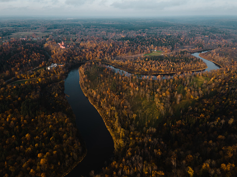 Establishing shot: Scenic autumn flight over Gauja river valley with Turaida castle in background