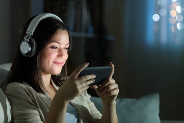 mulher relaxada assistindo vídeo à noite em casa - auscultador equipamento áudio - fotografias e filmes do acervo