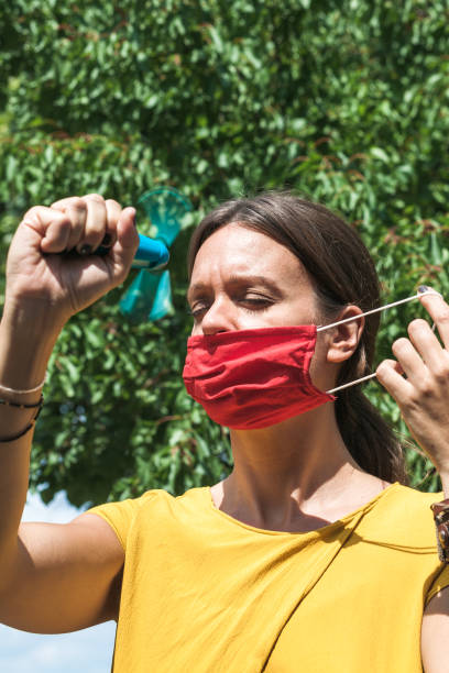istock young woman cooling down with hand held ventilator while wearing a protective face mask 1283544982