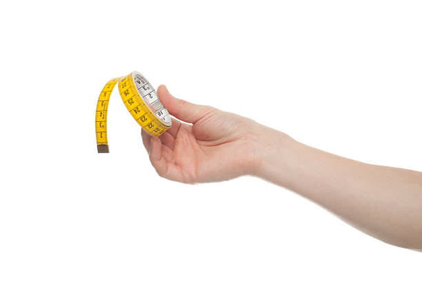 istock Hand holding a yellow measuring tape, isolated on white background 1283545271